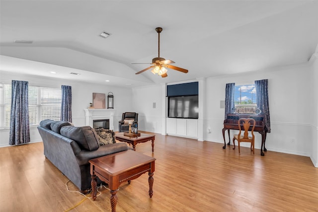 606 Packer Ct, Webster, TX 77598 - living room with lofted ceiling, plenty of natural light, light wood-style flooring, a ceiling fan, and a glass covered fireplace