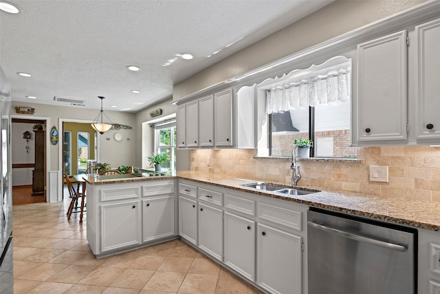 6207 Spring Creek Oaks Dr, Spring, TX 77379 - kitchen with stainless steel dishwasher, a sink, a peninsula, tasteful backsplash, and a textured ceiling