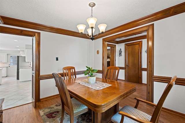 6207 Spring Creek Oaks Dr, Spring, TX 77379 - dining room with a chandelier, crown molding, baseboards, a textured ceiling, and light wood-style flooring
