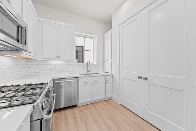 1511 Vermont St Unit A, Houston, TX 77006 - kitchen featuring appliances with stainless steel finishes, a sink, light wood-type flooring, backsplash, and white cabinetry