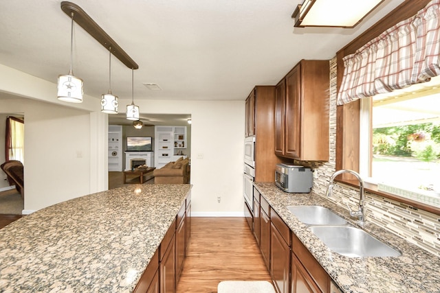 1576 Belle Terre Rd, Huffman, TX 77336 - kitchen featuring brown cabinets, oven, decorative backsplash, a sink, and light wood-type flooring