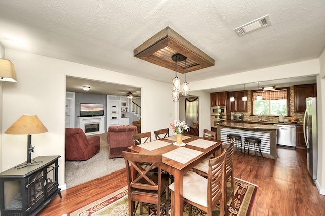 1576 Belle Terre Rd, Huffman, TX 77336 - dining area featuring dark wood-style floors, a wood stove, a ceiling fan, stairs, and a textured ceiling
