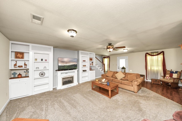 1576 Belle Terre Rd, Huffman, TX 77336 - living room with stairway, a ceiling fan, a fireplace, and a textured ceiling