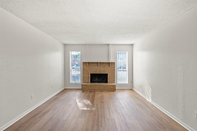 1516 Bay Area Blvd Unit Q1, Houston, TX 77058 - unfurnished living room featuring wood finished floors, a textured ceiling, a fireplace, baseboards, and a textured wall