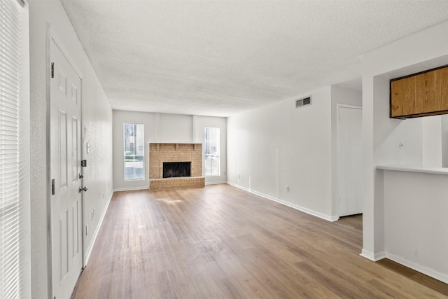 1516 Bay Area Blvd Unit Q1, Houston, TX 77058 - unfurnished living room with a textured ceiling, wood finished floors, baseboards, and a brick fireplace