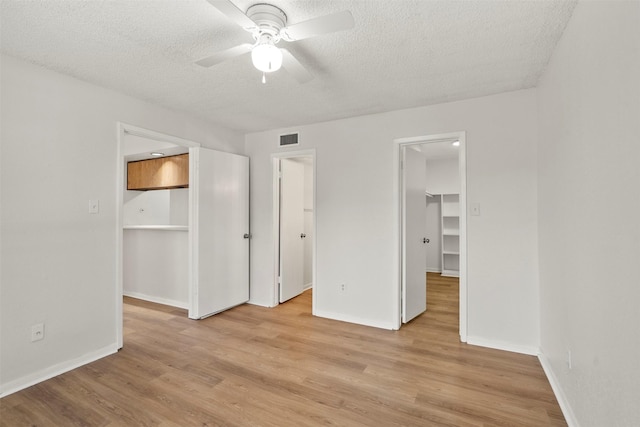 1516 Bay Area Blvd Unit Q1, Houston, TX 77058 - unfurnished bedroom featuring a spacious closet, a closet, a textured ceiling, light wood-style flooring, and baseboards