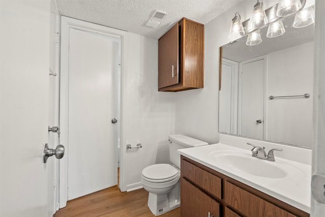 1516 Bay Area Blvd Unit Q1, Houston, TX 77058 - bathroom with wood finished floors, vanity, a textured ceiling, and toilet