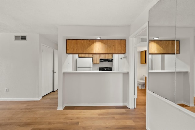1516 Bay Area Blvd Unit Q1, Houston, TX 77058 - kitchen featuring freestanding refrigerator, extractor fan, brown cabinets, light wood finished floors, and baseboards