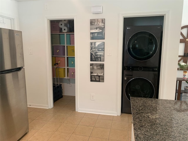 16520 Jasmine Marie Pl, Conroe, TX 77306 - laundry area with stacked washer / dryer, light tile patterned flooring, and baseboards