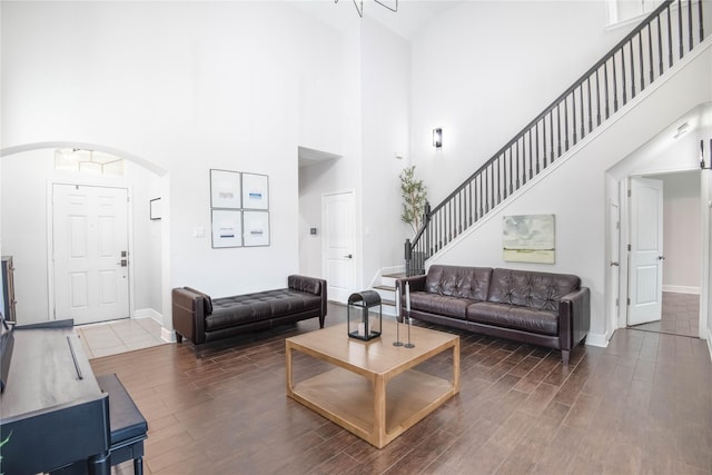 8926 Rollick Dr, Tomball, TX 77375 - living area featuring a high ceiling, arched walkways, wood finished floors, baseboards, and stairs