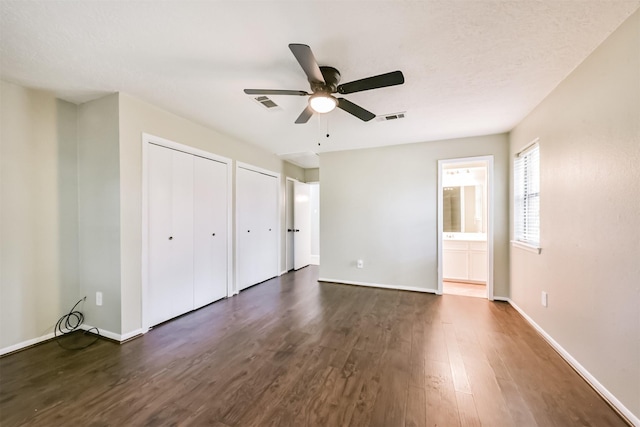 29090 W Lake Dr, Hempstead, TX 77445 - unfurnished bedroom featuring dark wood-style flooring, two closets, baseboards, and ceiling fan