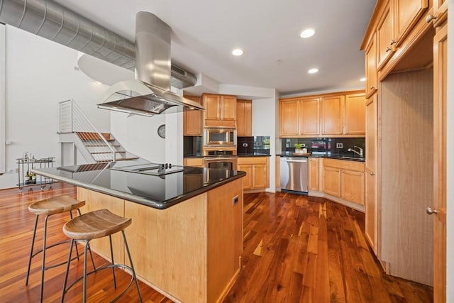 3030 Post Oak Blvd Unit 615, Houston, TX 77056 - kitchen featuring stainless steel appliances, island exhaust hood, dark wood finished floors, dark countertops, and recessed lighting