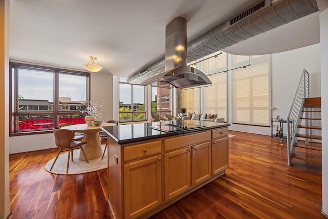 3030 Post Oak Blvd Unit 615, Houston, TX 77056 - kitchen with island range hood, dark wood-style flooring, dark countertops, black electric cooktop, and a kitchen island
