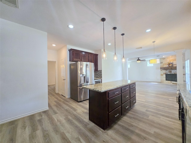 kitchen featuring stainless steel fridge with ice dispenser, light wood-style flooring, a fireplace, ceiling fan, and open floor plan