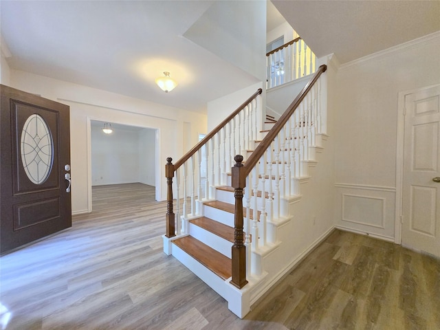 entrance foyer featuring wood finished floors, stairs, ornamental molding, and baseboards