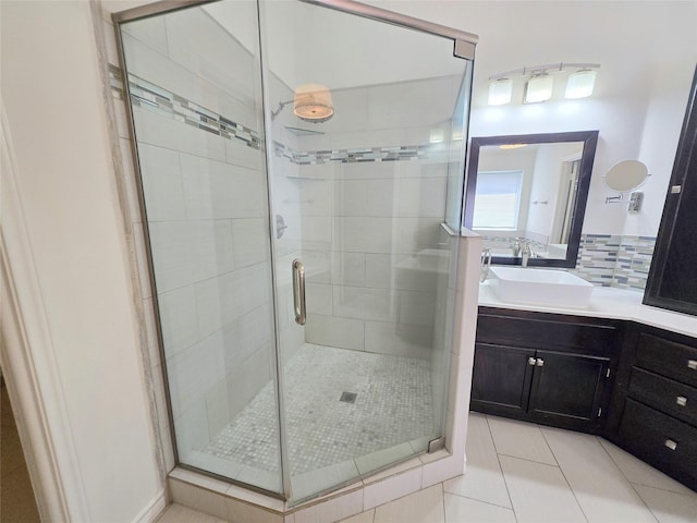 bathroom with tile patterned floors, vanity, a stall shower, and backsplash