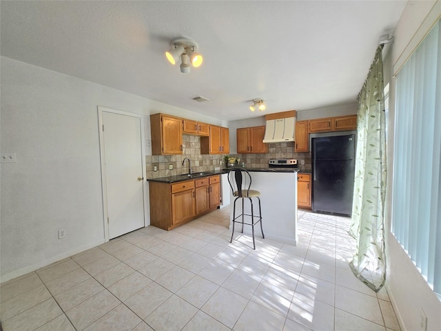 2922 Whetrock Ln, Sugar Land, TX 77479 - kitchen with freestanding refrigerator, wall chimney range hood, tasteful backsplash, dark countertops, and a sink
