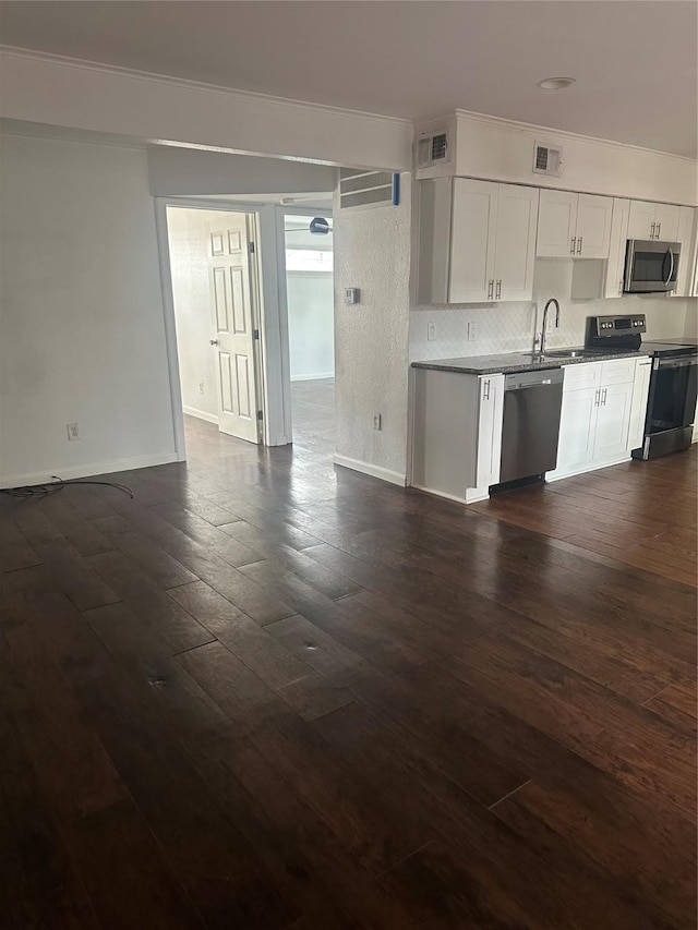 kitchen with appliances with stainless steel finishes, a sink, baseboards, dark wood-type flooring, and open floor plan