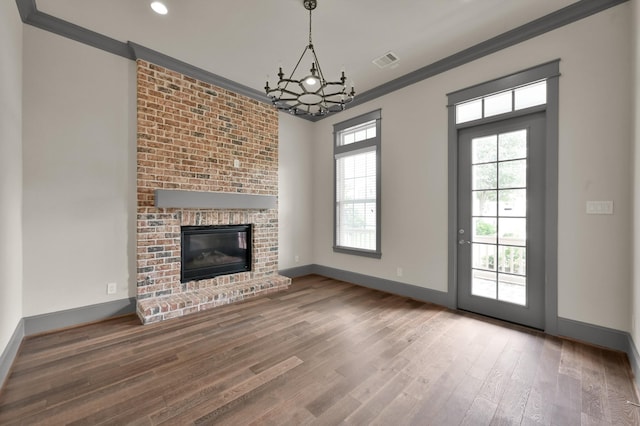 2331 Bottlebrush Ln, Conroe, TX 77384 - unfurnished living room featuring baseboards, wood finished floors, a chandelier, crown molding, and a fireplace
