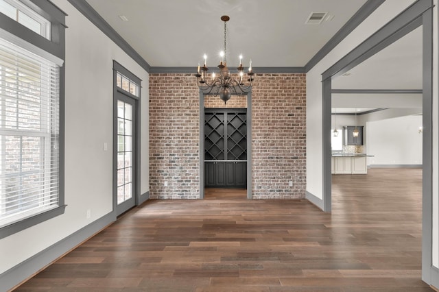 2331 Bottlebrush Ln, Conroe, TX 77384 - unfurnished dining area with ornamental molding, a chandelier, healthy amount of natural light, brick wall, and wood finished floors