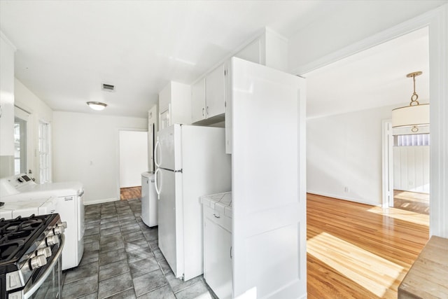 2740 Suffolk Dr, Houston, TX 77027 - kitchen featuring freestanding refrigerator, white cabinetry, gas stove, baseboards, and washer and dryer