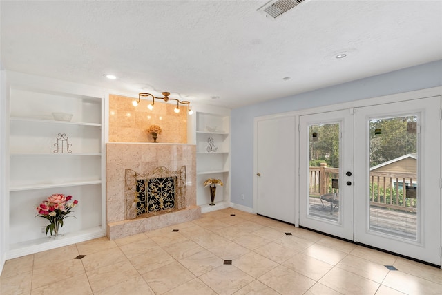 3525 Elm Dr, Dickinson, TX 77539 - unfurnished living room with french doors, built in features, a high end fireplace, a textured ceiling, and baseboards