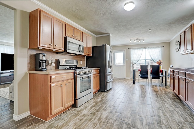 10911 Crosby Field Ln, Houston, TX 77034 - kitchen featuring stainless steel appliances, light wood finished floors, ornamental molding, a textured ceiling, and light countertops