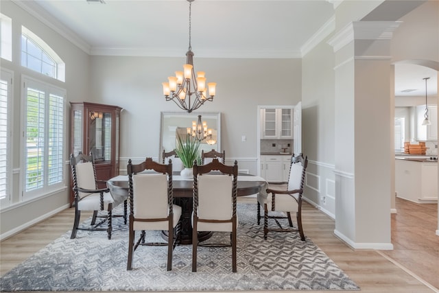 dining space with plenty of natural light, arched walkways, crown molding, a chandelier, and light wood-style floors