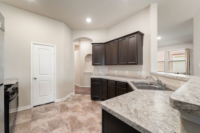 10750 Nathaniel Valley Path, Houston, TX 77016 - kitchen featuring a sink, arched walkways, dark brown cabinets, light countertops, and black gas stove