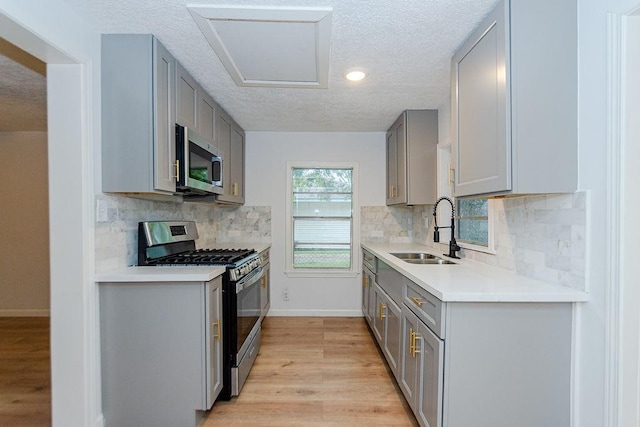 2425 E Fayle St, Baytown, TX 77521 - kitchen with stainless steel appliances, a sink, gray cabinetry, a textured ceiling, and light wood-type flooring