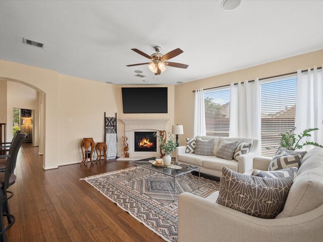 22603 Blanefield Ct, Tomball, TX 77375 - living room featuring arched walkways, a ceiling fan, dark wood finished floors, a glass covered fireplace, and baseboards