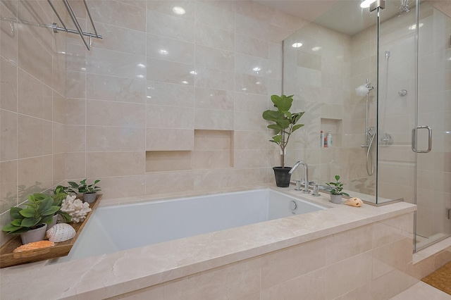 2207 Bancroft St Unit 604, Houston, TX 77027 - bathroom featuring a stall shower, a bath, and tile walls