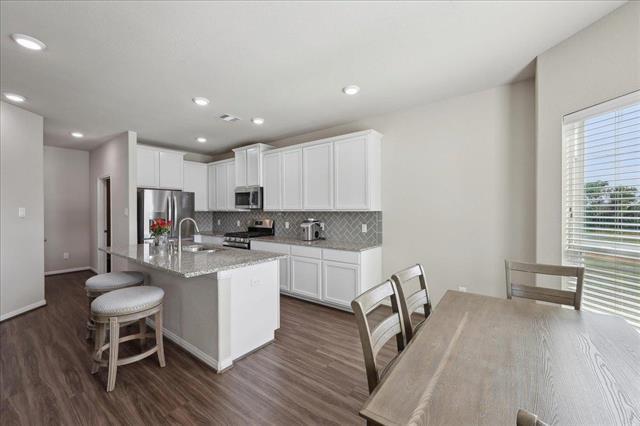 2498 Diamond D Dr, Beaumont, TX 77713 - kitchen with appliances with stainless steel finishes, dark wood-type flooring, a sink, tasteful backsplash, and a kitchen island with sink