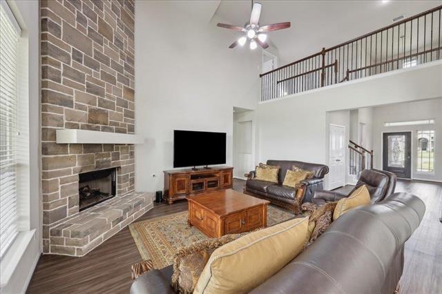 2498 Diamond D Dr, Beaumont, TX 77713 - living room with a towering ceiling, a ceiling fan, dark wood-style flooring, a fireplace, and stairs