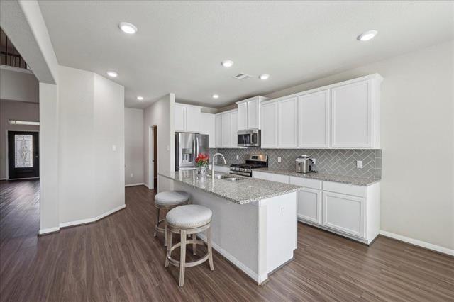 2498 Diamond D Dr, Beaumont, TX 77713 - kitchen with stainless steel appliances, a sink, dark wood finished floors, baseboards, and decorative backsplash