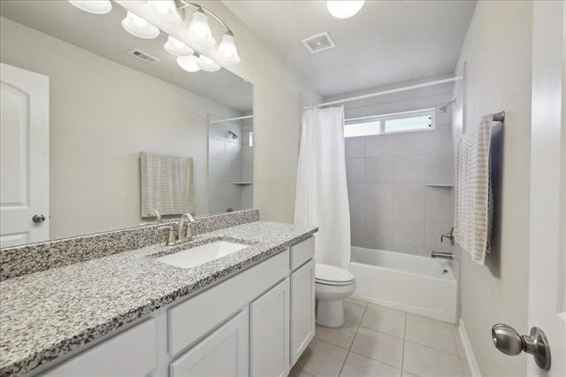 2498 Diamond D Dr, Beaumont, TX 77713 - full bath with tile patterned floors, toilet, vanity, shower / bath combo with shower curtain, and baseboards