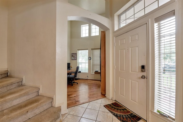13111 Porter Meadow Ln, Houston, TX 77014 - entrance foyer with arched walkways, light tile patterned floors, a high ceiling, stairway, and baseboards