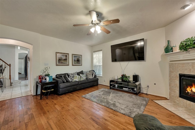 13111 Porter Meadow Ln, Houston, TX 77014 - living room featuring arched walkways, ceiling fan, wood-type flooring, and a tiled fireplace
