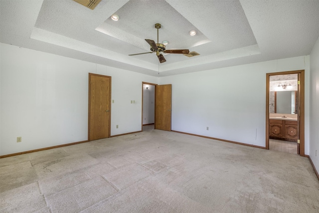 207 Oak Hill Dr, Brenham, TX 77833 - unfurnished bedroom with a raised ceiling, light carpet, baseboards, and a textured ceiling