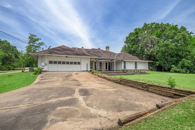 207 Oak Hill Dr, Brenham, TX 77833 - single story home featuring a garage, concrete driveway, a front yard, a chimney, and board and batten siding