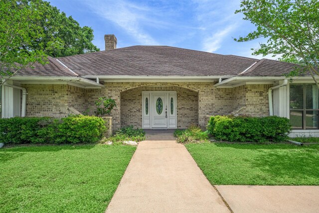 207 Oak Hill Dr, Brenham, TX 77833 - property entrance featuring a chimney, brick siding, and a lawn