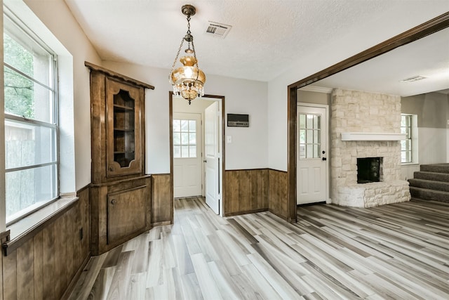 28902 Twisted Oak Dr, Shenandoah, TX 77381 - unfurnished dining area featuring wainscoting, plenty of natural light, a fireplace, light wood-style flooring, and a chandelier