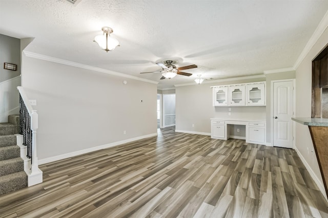 28902 Twisted Oak Dr, Shenandoah, TX 77381 - unfurnished living room with stairs, a textured ceiling, a ceiling fan, light wood-type flooring, and crown molding