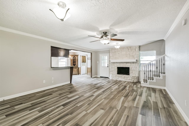 28902 Twisted Oak Dr, Shenandoah, TX 77381 - unfurnished living room featuring baseboards, plenty of natural light, wood finished floors, ornamental molding, and a textured ceiling
