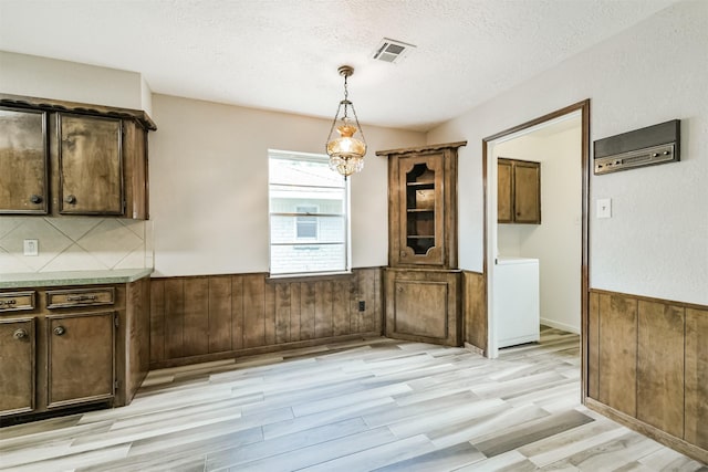 28902 Twisted Oak Dr, Shenandoah, TX 77381 - unfurnished dining area featuring wainscoting, light wood-style flooring, a textured ceiling, wooden walls, and washer / dryer