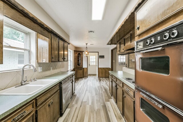 28902 Twisted Oak Dr, Shenandoah, TX 77381 - kitchen with a sink, light wood-type flooring, stainless steel dishwasher, pendant lighting, and a wainscoted wall