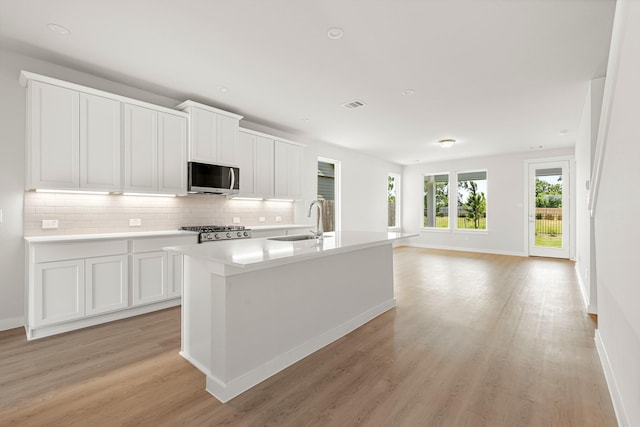 33019 School Hill Rd, Fulshear, TX 77441 - kitchen featuring stainless steel microwave, a sink, light wood-style floors, tasteful backsplash, and range