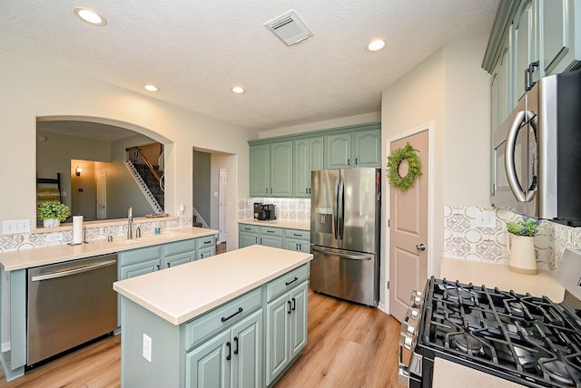 13907 Pawnee Trails Dr, Cypress, TX 77429 - kitchen featuring stainless steel appliances, green cabinets, a center island, arched walkways, and light countertops