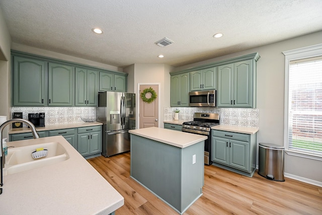 13907 Pawnee Trails Dr, Cypress, TX 77429 - kitchen featuring stainless steel appliances, a sink, a center island, light countertops, and green cabinetry