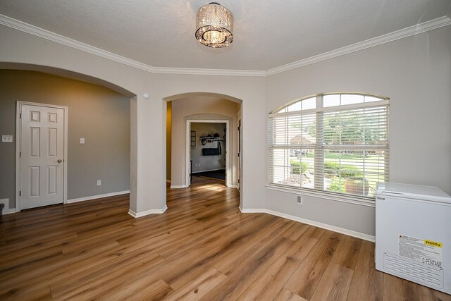 13907 Pawnee Trails Dr, Cypress, TX 77429 - spare room with arched walkways, ornamental molding, light wood-style floors, baseboards, and a chandelier